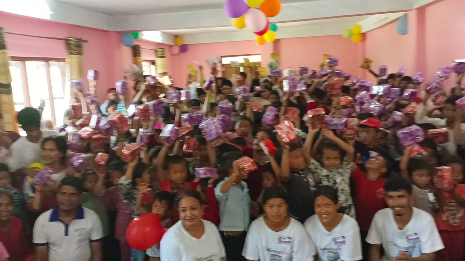 A joyful crowd of children holding up their Christmas gifts