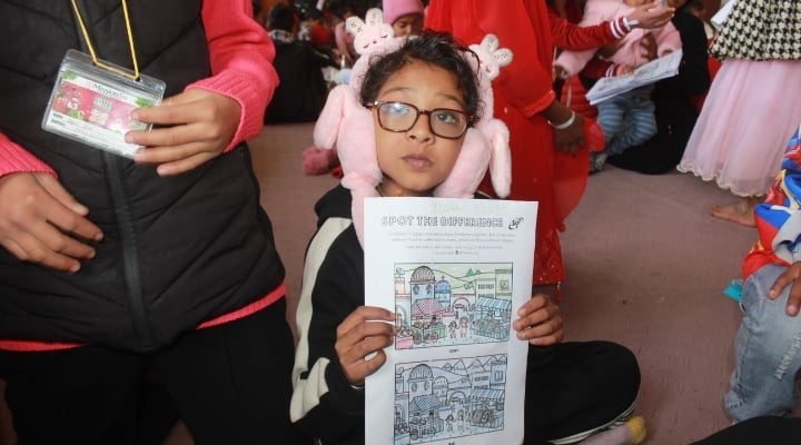 A girl proudly showing her activity worksheet